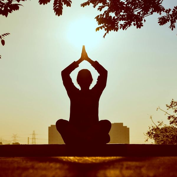 Silhouette of a person meditating during sunrise.